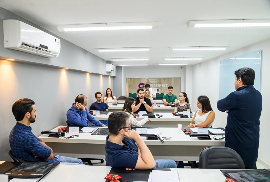 Instrutor e alunos participando de uma discussão ativa sobre Implantodontia no Instituto IPPO, promovendo troca de conhecimentos.