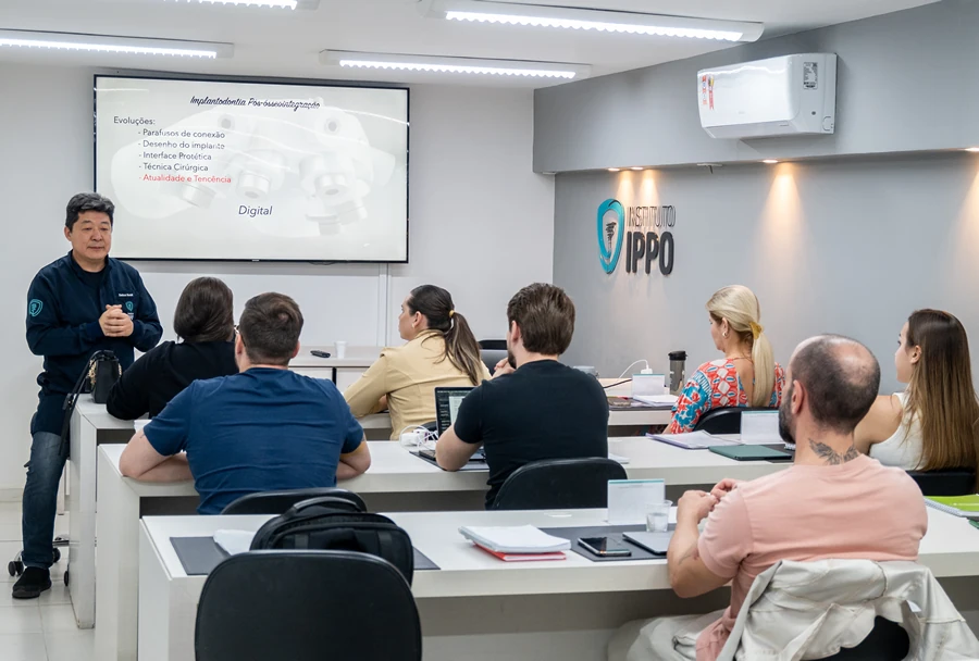 Aula sobre Implantodontia, com o instrutor explicando tópicos avançados para um grupo de alunos atentos no Instituto IPPO.