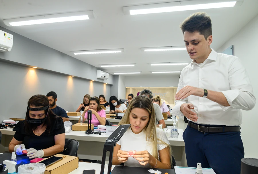 Em uma sala escura com luz azul, alunos do Instituto IPPO realizam atividades práticas supervisionadas pelo instrutor.